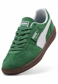 Baskets Puma Palermo en daim vert avec une bande blanche, une semelle marron et des lacets verts, présentées en angle pour montrer les détails latéraux et supérieurs.