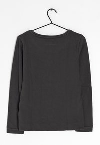 Chemise à manches longues de couleur gris foncé, en coton doux. Dotée d'un col arrondi et de poignets simples ourlés. Suspendue à un cintre noir.