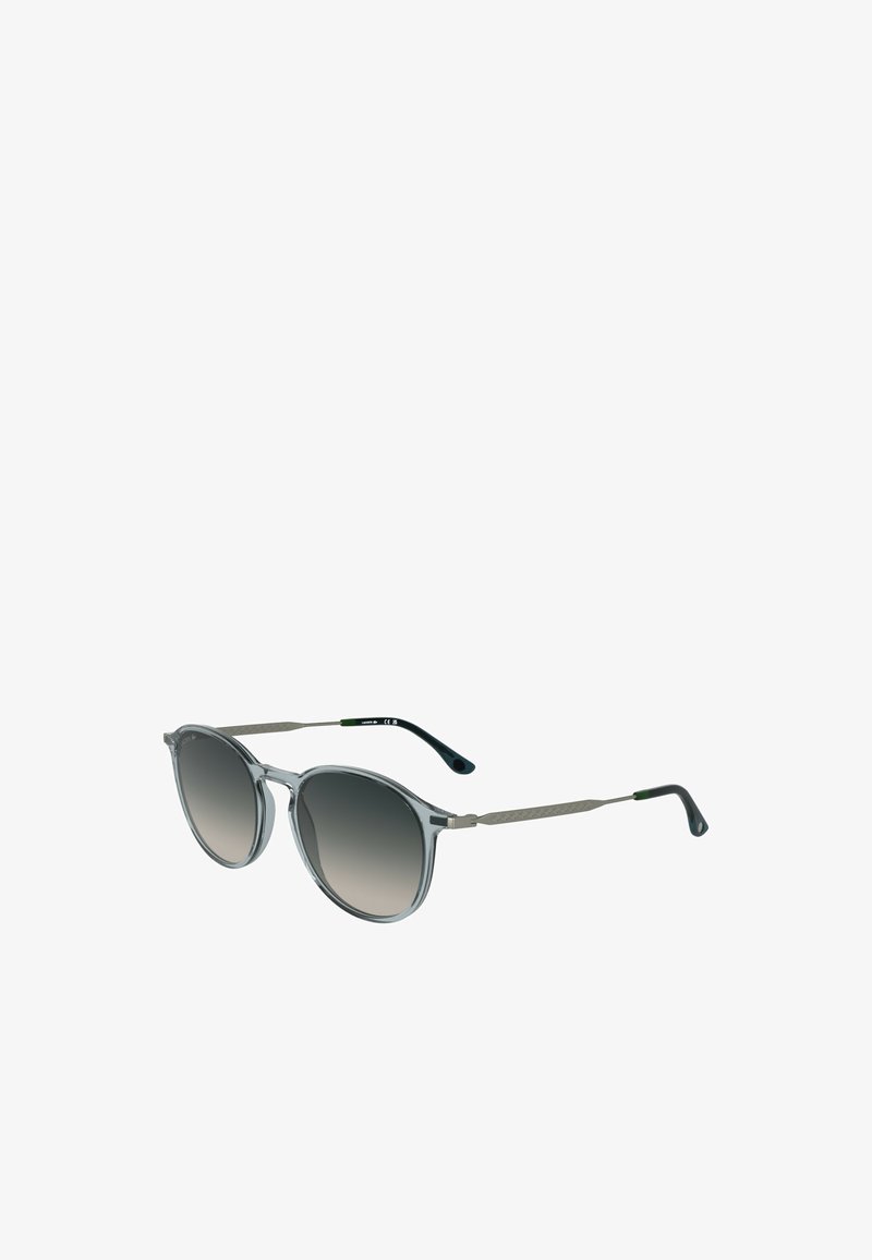 Apvalūs akiniai nuo saulės su skaidriu pilku rėmeliu, gradientinėmis tamsiomis lęšiais ir metaliniais sidabro akcentais ant šventyklų. Textūruotos šakutės tamsiai mėlynos spalvos.