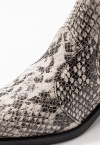 Stiefel aus strukturiertem, schwarzem und weißem Kunstschlangenleder mit spitzem Zeh, seitlichen Nähten und einer glatten schwarzen Sohle.
