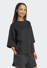 Sort oversized t-shirt med rund halsudskæring, korte ærmer og afslappet pasform, kombineret med matchende sorte shorts. Blødt, glat stof.