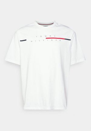 Biała koszulka z krótkim rękawem i okrągłym dekoltem, z napisem "Tommy Hilfiger" oraz poziomym czerwono-niebieskim paskiem na wysokości klatki piersiowej.