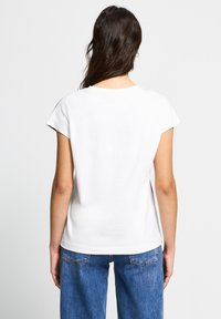 Hvid bomulds t-shirt med rund hals og korte ærmer, der har en afslappet pasform og glat tekstur, vist fra ryggen.