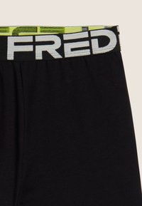 Pantaloncini neri con una cintura elastica caratterizzata da un logo "FRED" prominente in bianco su uno sfondo a motivo giallo e nero nella parte superiore.