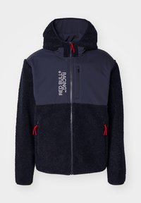 Marine fleecejack met een zachte textuur, rode accenten, volledige ritssluiting en logo-opdruk. Heeft een capuchon en twee ritszakken aan de zijkanten.