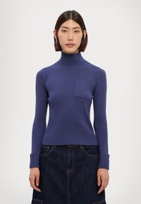 Rippstrick-Turtleneck-Pullover in Dunkelblau mit langen Ärmeln und einer Brusttasche. Aus weichem Material gefertigt, zeichnet er sich durch eine taillierte Passform und eine strukturierte Oberfläche aus.