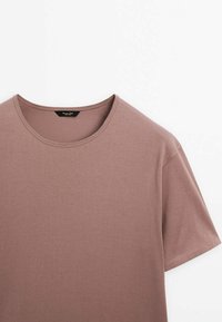 T-shirt manches courtes couleur rose poussiéreux avec col rond et coutures visibles sur fond blanc.