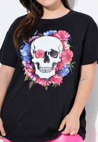 Sort t-shirt med et stort kraniumdesign omkranset af farverige blomsterelementer, med en glat tekstur og afslappet pasform.