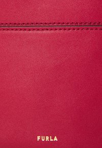 Sac à main en cuir rouge avec une finition texturée, présentant des détails de couture et un logo "Furla" doré en bas.