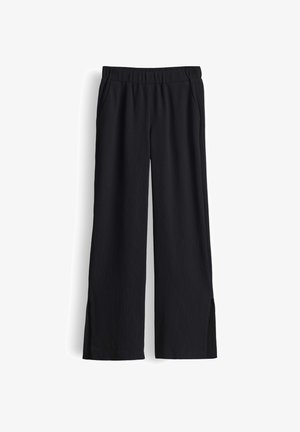 Pantaloni neri a gamba larga con vita elasticizzata e spacchi laterali all’orlo, realizzati in tessuto crêpe leggero.