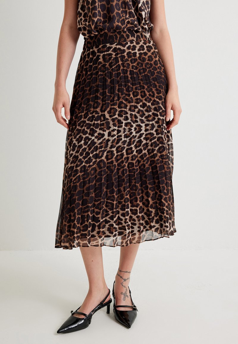 Gonna midi plissettata in stampa leopardata in tessuto leggero, con una vita nera, abbinata a décolleté slingback nere con punta a punta.