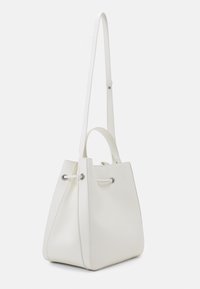 Bolso tipo cubo blanco hecho de cuero texturizado con ojales de tono plateado y cierre de cordón; cuenta con una correa larga ajustable y asas cortas.