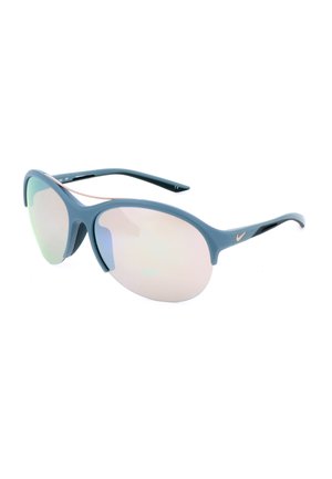Occhiali da sole sportivi con montatura blu, lenti ovali riflettenti e piccolo logo Nike argentato sulla stanghetta, esposti su sfondo bianco.