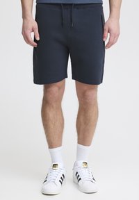 Navyblauwe sweatshorts van een textuurstof, met een elastische tailleband en een trekkoord. Heeft zijzakken met rits en een rechte snit.