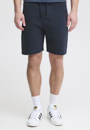 Pantaloni scurți de trening bleumarin dintr-un material texturat, cu un elastic la talie și șnur. Dispun de buzunare laterale cu fermoar și au o croială dreaptă.