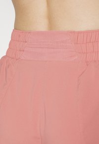 Pantalones rosa de cintura elástica con una textura suave, que presentan costuras cosidas y un detalle de cinturilla fruncida. Material ligero y transpirable.