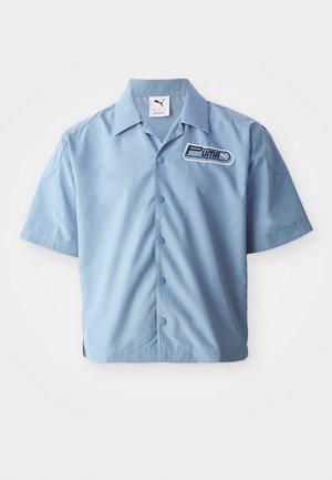 Lys blå kortærmet skjorte med knapper lavet af glat stof. Har et sort og hvidt Puma-logo på venstre bryst. Klassisk kravedesign.