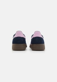 Marineblå semskede sneakers med rosa detaljer og en struktureret brun gummisål. Lave sneakers med en glat ryg og kontrasterende hældetalje.