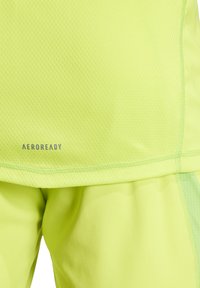 Top atletico verde lime con tessuto testurizzato e pantaloni larghi lisci, con marchio AEROREADY e accenti di cucitura a contrasto.