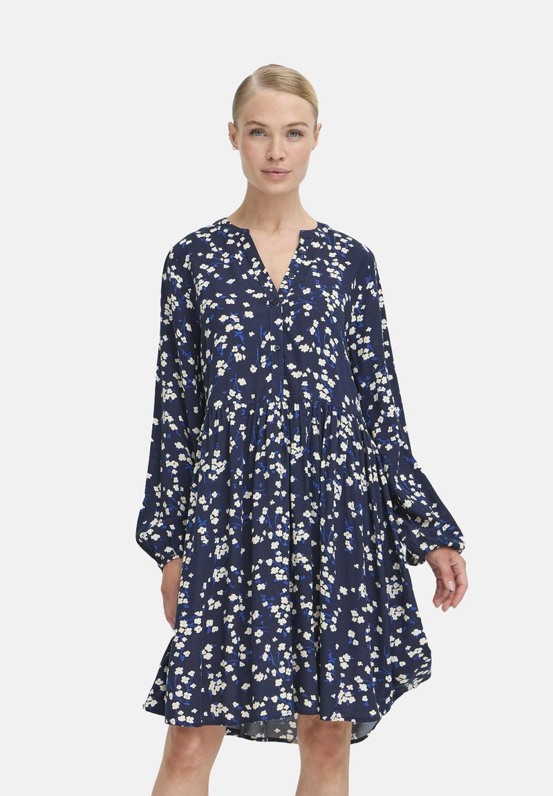 Marineblaues Kleid mit langen Ärmeln, Blumenmuster in Weiß und Blau, V-Ausschnitt, geraffte Taille und ausgestellter Rock.
