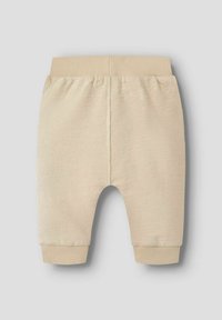 Beige geribbelde peuterbroek met een elastische tailleband en boorden, met een zachte textuur en een ronde snit bij de pijpopeningen.