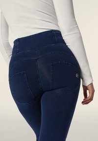 Hogezit denim leggings in donkerblauw. Kenmerken een gladde textuur, gestikte naden en twee achterzakken met een klein logo-detail.