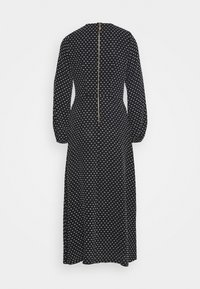 Černé šaty s bílými puntíky, dlouhé rukávy, stažený pas a zip na zadní straně. Délka po zem, hladká textura a standardní střih.