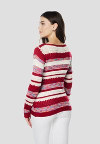 Gebreide trui met rood-wit en kleurrijke gestreepte patronen, voorzien van een ronde hals en lange mouwen met opengebreide details.