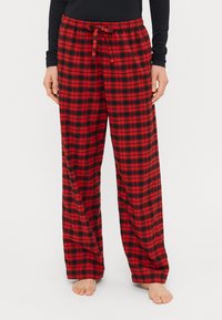 Rød og sort ternet pyjamabukser med løs pasform, elastisk talje og snøre, lavet af blødt materiale, velegnet til afslappet brug.