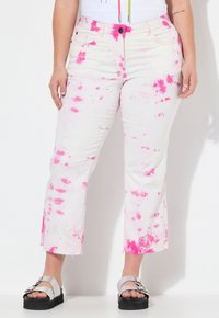 Vita denimjeans med rosa spräckligt mönster, fransad nederkant och en avslappnad passform. Har fem fickor och knappstängning.