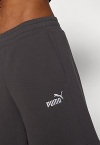 Donkergrijze shorts van een katoenmix, met een elastische tailleband en een witte geborduurde Puma-logo aan de linkerkant.