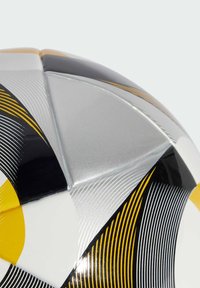 Fudbalska lopta s dizajnom u srebrnoj i crnoj boji, koja sadrži zakrivljene žute naglaske i prugaste uzorke. Glatka tekstura s sjajnom završnom obradom.