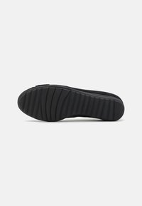Suola di sneaker nera in gomma testurizzata, con scanalature orizzontali e punta arrotondata, progettata per trazione e durata.