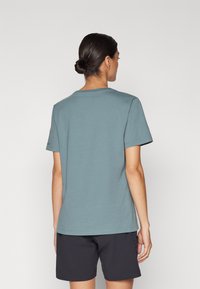 Basic short-sleeve t-shirt in muted teal cotton. Crew neck design with a relaxed fit. Smooth texture, displayed with dark shorts.