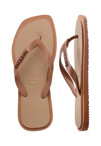 Paire de tongs beige avec semelles texturées et brides à motif zigzag, affichant le nom de la marque et les indications de taille sur les semelles.