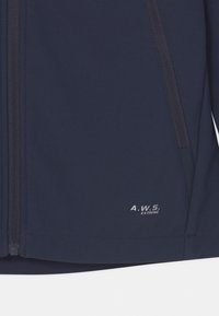 Granatowa kurtka softshell o gładkiej teksturze, z pełnym zapięciem na zamek i kieszeniami po bokach. Posiada logo "A.W.S. EXTREME" w białym kolorze blisko dołu.