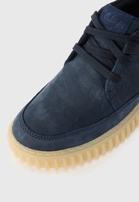 Navy leather shoe featuring textured upper, round toe, tonal laces, and a chunky gum rubber sole with vertical ribbing.