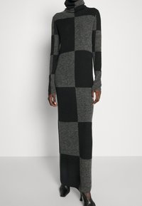 Lång turtleneckklänning i rutigt mönster, med nyanser av grått och svart. Stickat tyg med en figurnära silhuett och långa ärmar.