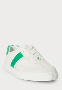 Valged sportlikud kingad roheliste suedekatete aktsentidega, tekstureeritud kummitald, seotud esiosa ja logo keeles. Üldiselt sile viimistlus.