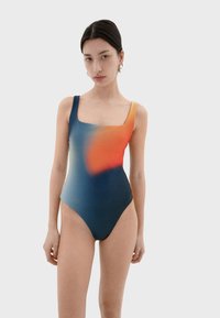 Jednodílné plavky s čtvercovým výstřihem, s gradací modrých, oranžových a černých odstínů. Hladká textura a minimalistický design.