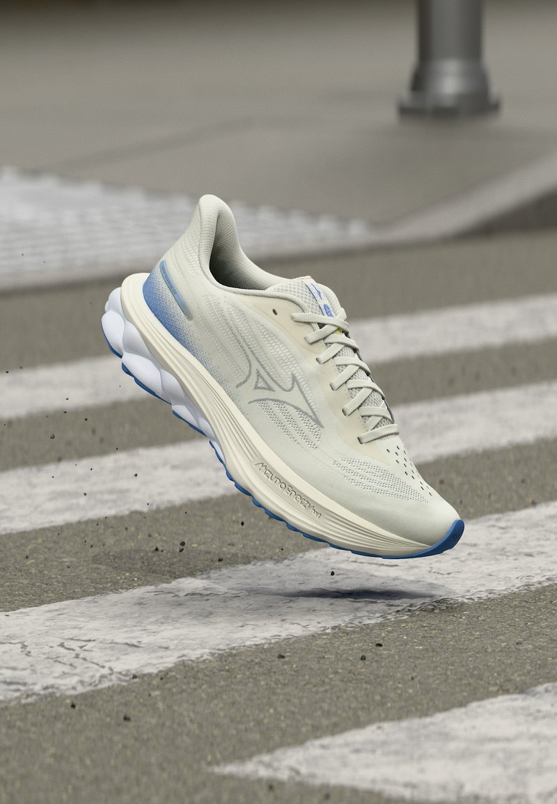 Λευκό και μπλε αθλητικό παπούτσι στον αέρα πάνω από διάβαση πεζών σε ασφάλτινο δρόμο, με λεπτομέρειες στο πλάι και στη σόλα του παπουτσιού.