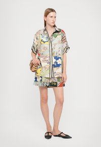 Colorful patchwork shirt and shorts set in silk blend with botanical and geometric patterns; paired with a woven bag and flat shoes.