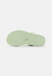 Suela de sandalia verde clara con un patrón geométrico texturizado. Presenta un logo grabado en el lateral. Material duradero para agarre y soporte.