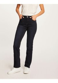 Donkerblauwe denim jeans met een hoge taille, vijf-pocket ontwerp, contrasterende stiksel en een slim fit, gecombineerd met witte sneakers.