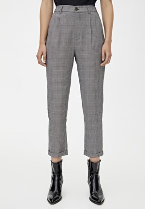 Person wearing gray plaid tapered ankle pants with cuffs and black pointed-toe ankle boots against a plain background.