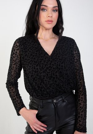 Black sheer top with a leopard print pattern, V-neckline, long sleeves, and textured fabric paired with high-waisted black pants.