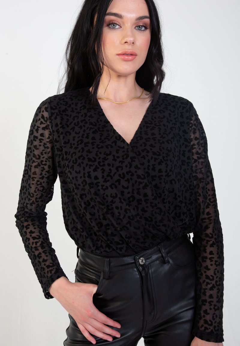 Black sheer top with a leopard print pattern, V-neckline, long sleeves, and textured fabric paired with high-waisted black pants.