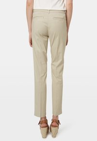 Kakifärgade byxor med slim fit, med bakfickor och en slät yta. Kombineras med bruna kilklacksandaler.