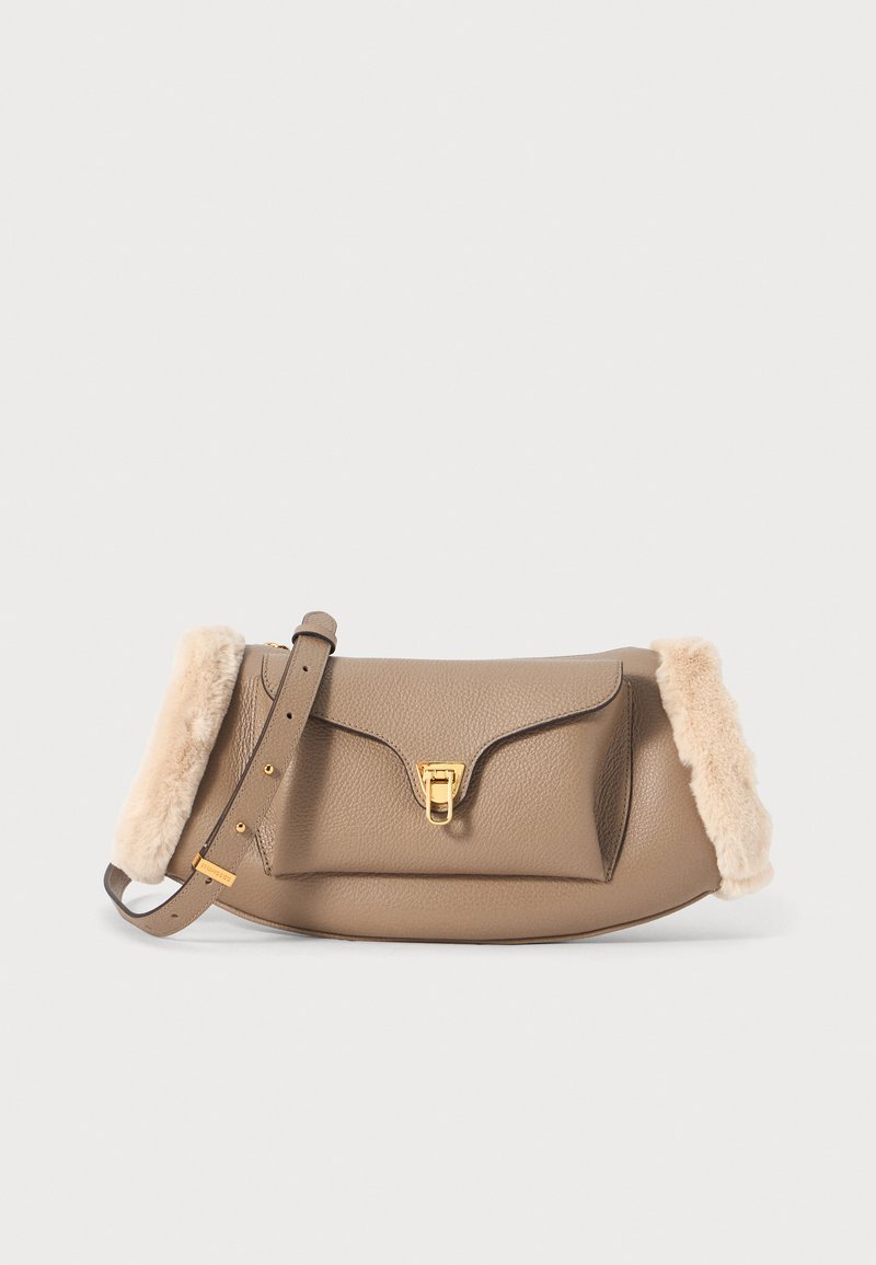 Borsa in pelle beige con un bordo in crema morbido, hardware dorato, chiusura a pattina e tracolla regolabile. Texture liscia.