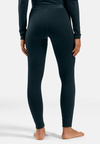 Black leggings made of a soft, stretchy material, featuring a fitted design and ankle cuffs, viewed from the back.